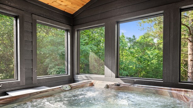 A hot tub with a wooden ceiling and large windows offering a view of a forest. - Sage Creek: Secluded Family Getaway | Large Deck (Broken Bow)