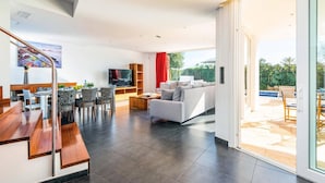 A modern living room with a sofa, TV, and dining area.