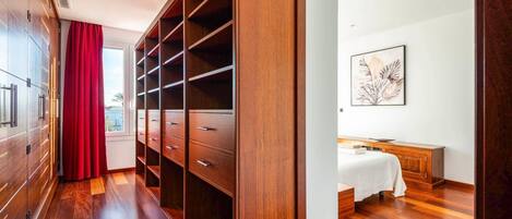 Una habitación de hotel moderna con un armario de madera, una cama con cubrecama blanco y una obra de arte colgada en la pared.