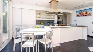 A modern kitchen with a central island, white cabinetry, and a large window.