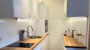 A modern kitchen with white cabinets, a wooden countertop, a stainless steel sink, and a built-in oven. - 20m from ski slopes, 3rd floor, balcony, parking, 50m², Vars (Vars)