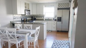 Una cocina moderna con armarios blancos, encimera de granito y microondas integrado.