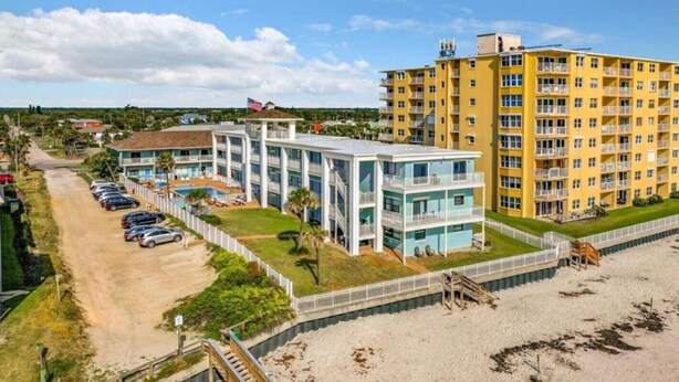 A beachfront hotel with multiple buildings, a parking area, and a swimming pool. - Pool View Studio Suite #109 (New Smyrna Beach)