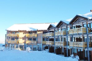 Un hotel de varios pisos con balcones y un paisaje cubierto de nieve.