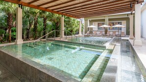 A pool area with two pools, palm trees, and lounge chairs under a wooden pergola. - Luxury 4-Bedroom Condo with Stunning Views – Poro 4A (Santa Cruz)