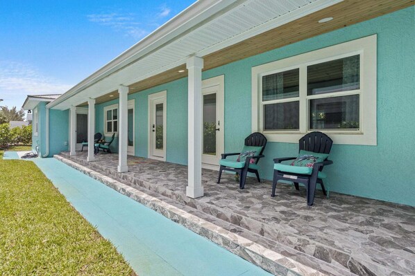 A house with a covered porch, stone steps, and two chairs. - Ocean Drive Villas- Unit A (Fort Pierce)