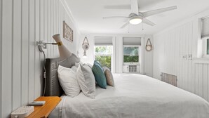 Un dormitorio con cama, mesita de noche y ventilador de techo.