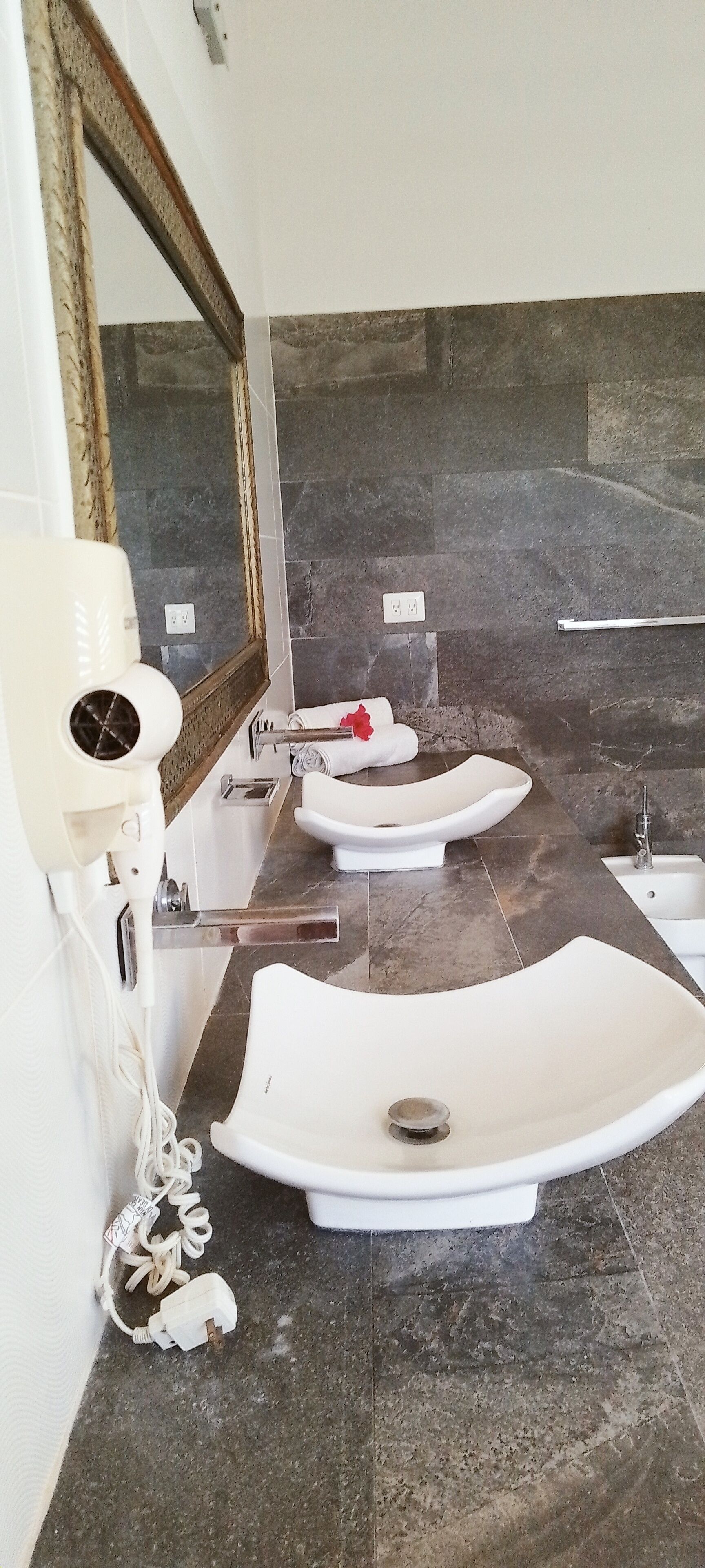 A bathroom with two sinks, a hairdryer, and a towel rack.