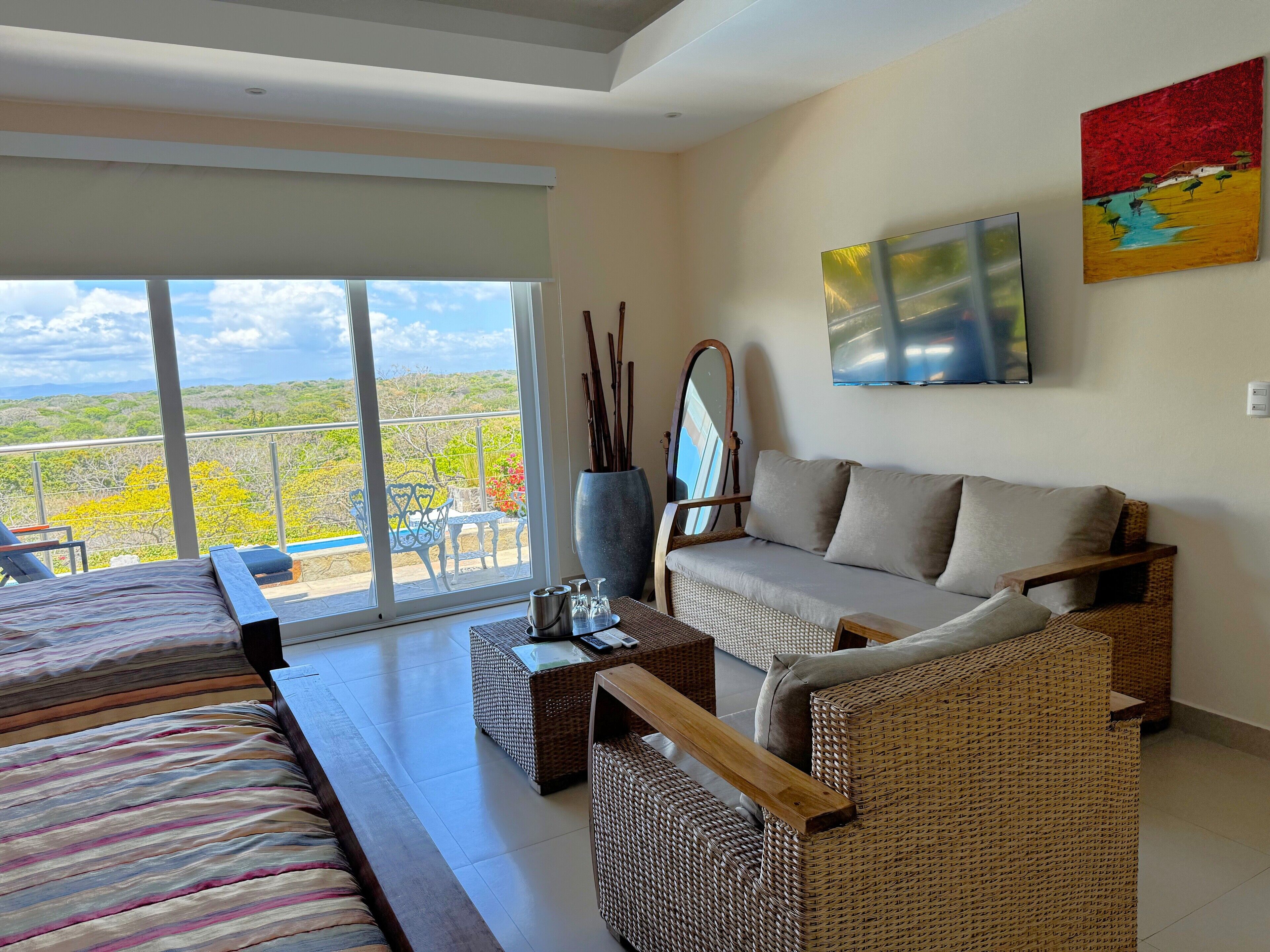 A modern room with a large window, a sofa, a bed, and a flat-screen TV.