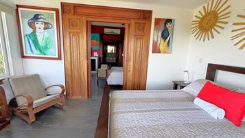 Una habitación de hotel con una cama, una silla, un escritorio y una puerta que da a otra habitación.