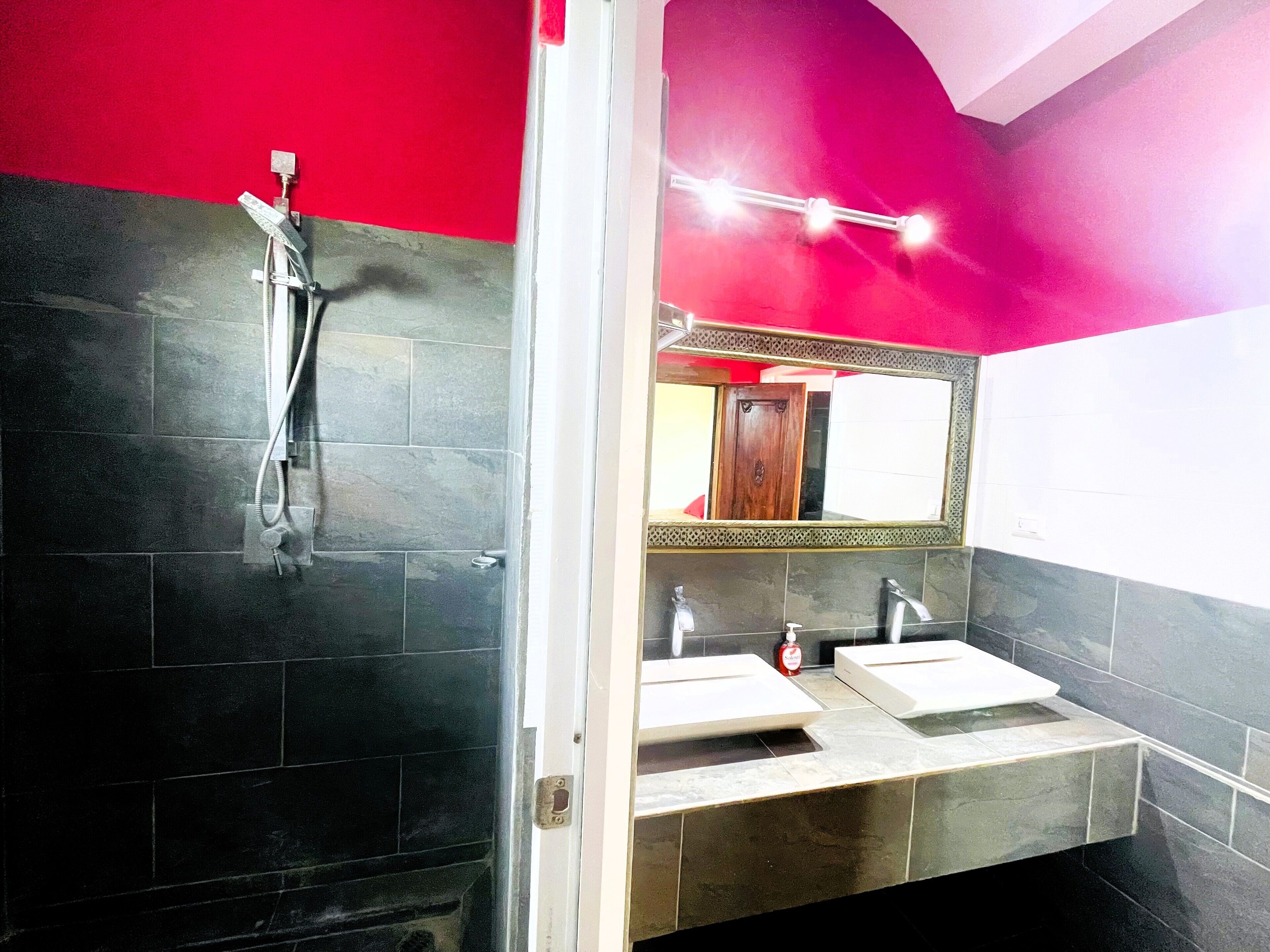 A bathroom with a shower, two sinks, and a mirror.