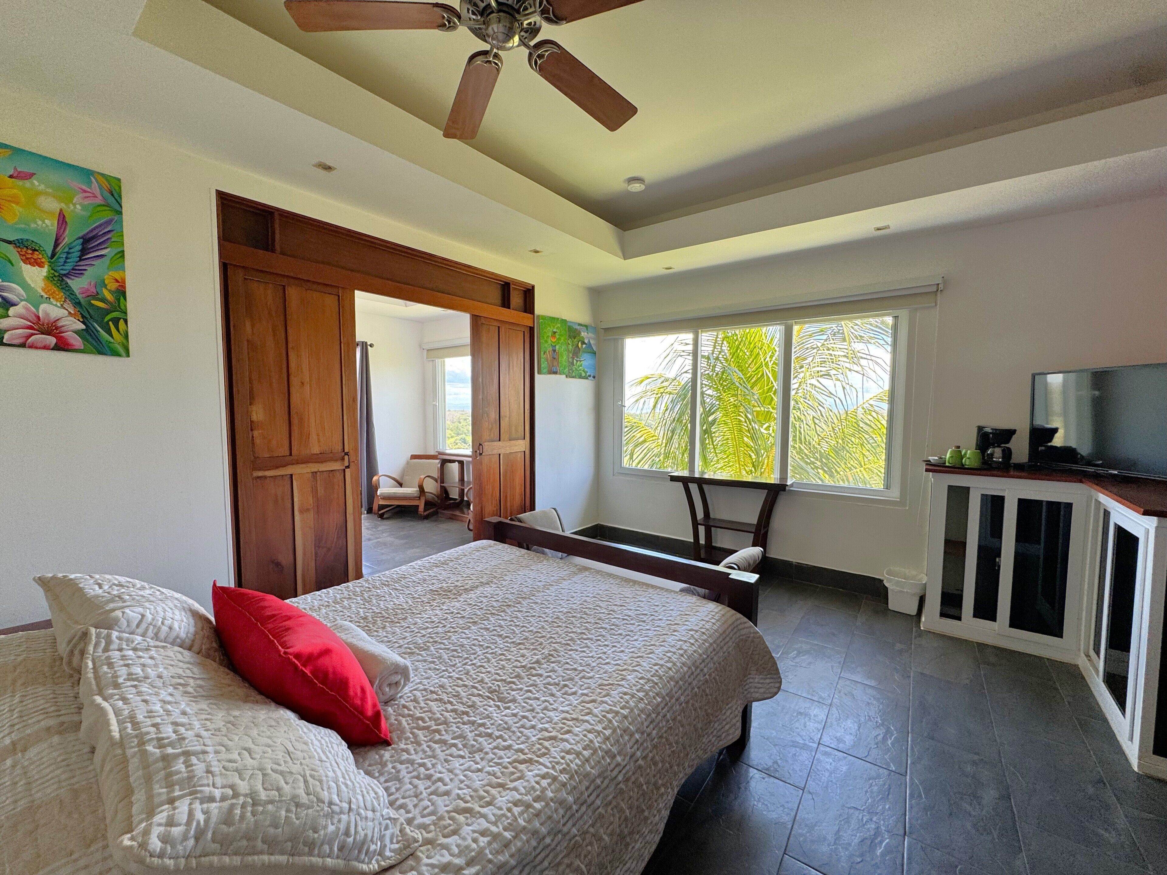 Un dormitorio con cama, televisor, escritorio y ventana con vistas.