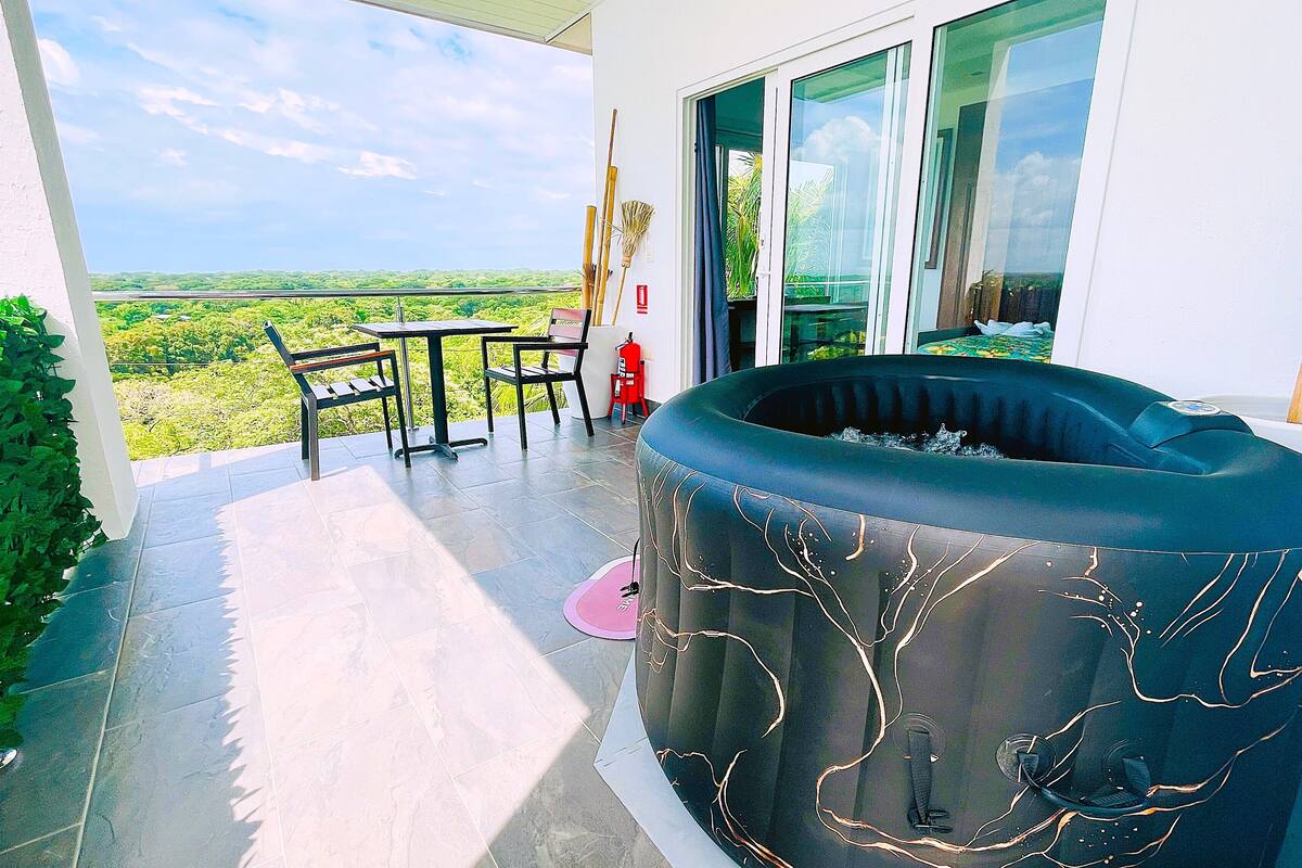Ein Balkon mit Whirlpool, Tisch und Stühlen mit Blick auf eine üppige Landschaft.