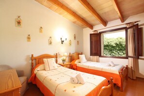 Une chambre avec deux lits en bois, une fenêtre avec des rideaux et des  éléments de décoration fixés au mur.