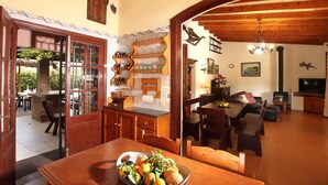 A spacious kitchen with wooden cabinets, a dining area with a table set for four, and a living room with a sofa and a television. - H2933 Finca Tia in Pollenca (Pollenca)