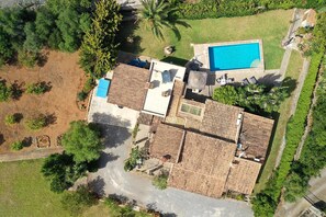 Vue aérienne d’une propriété comprenant une piscine, plusieurs bâtiments et un espace vert environnant.