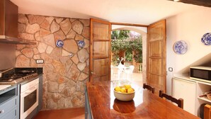 A kitchen with a stone wall, wooden cabinets, and a dining area with a table and chairs. - H2935 Finca Solivelles in Pollenca for 8 persons (Pollenca)