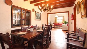 A dining area with a wooden table and chairs, a chandelier, and a large cabinet with glass doors. - H2935 Finca Solivelles in Pollenca for 8 persons (Pollenca)