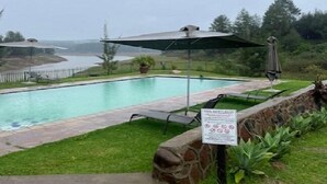 A swimming pool with a stone border, a lounge chair, and a sign with safety rules. - Lake Alexander Country Resort  (Penhalonga)