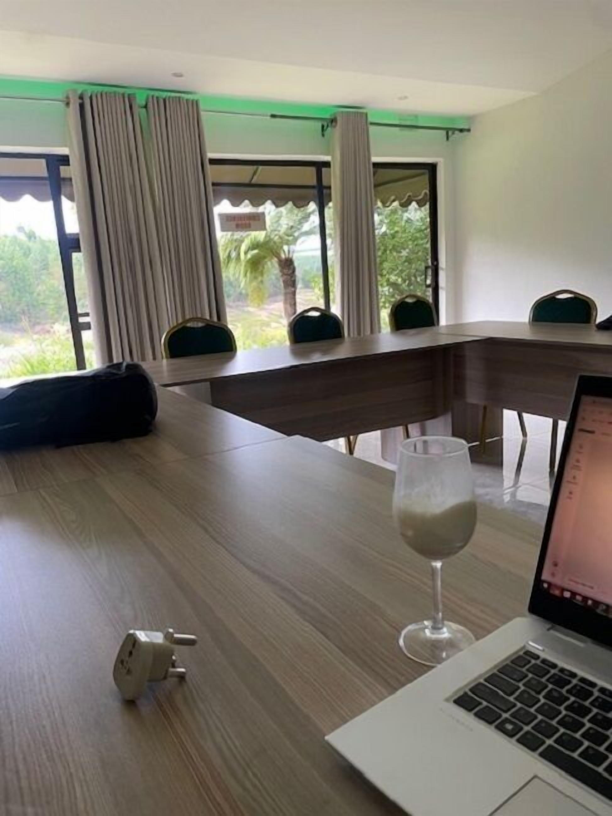 A conference room with a long table, chairs, a laptop, and a glass of water.
