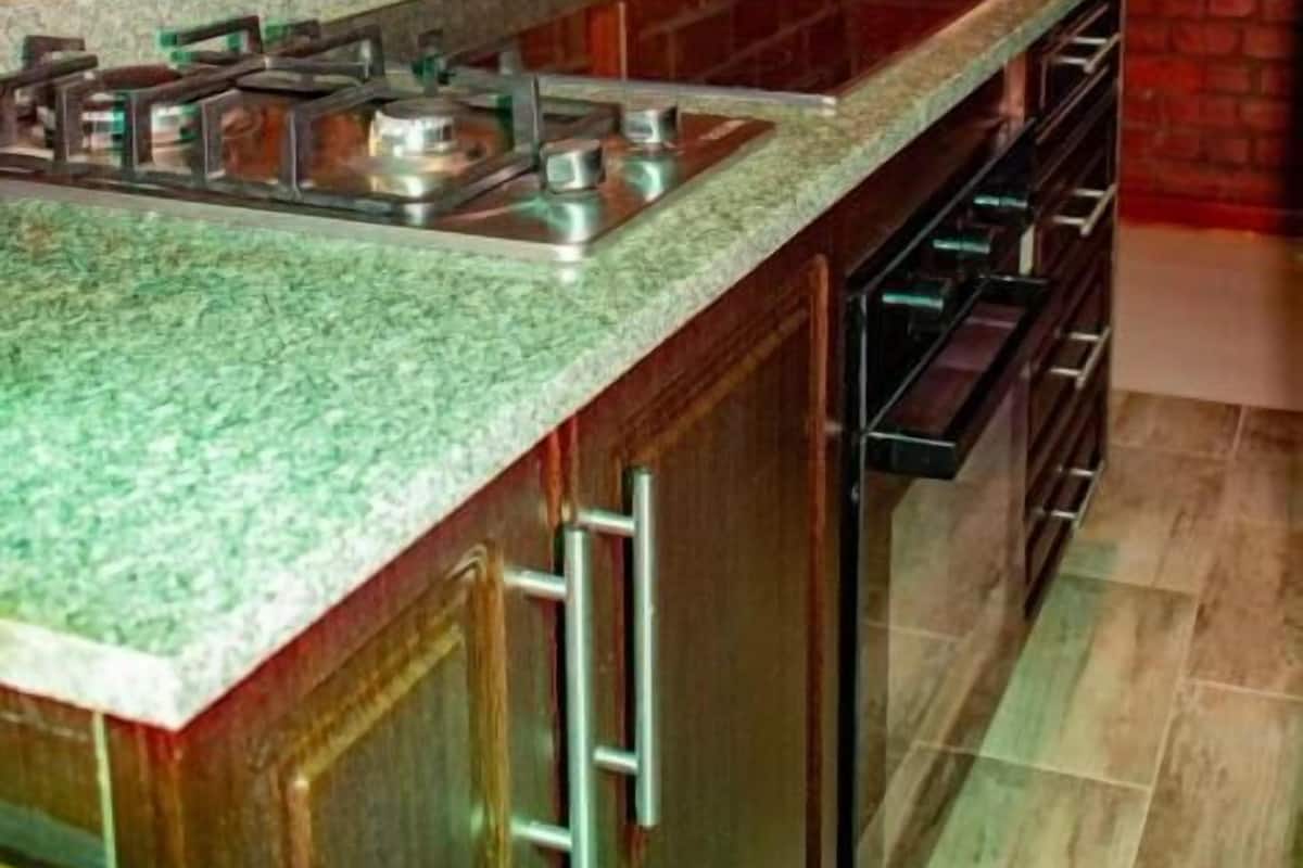 Cozinha com bancada de granito, fogão de aço inoxidável e armários de madeira.