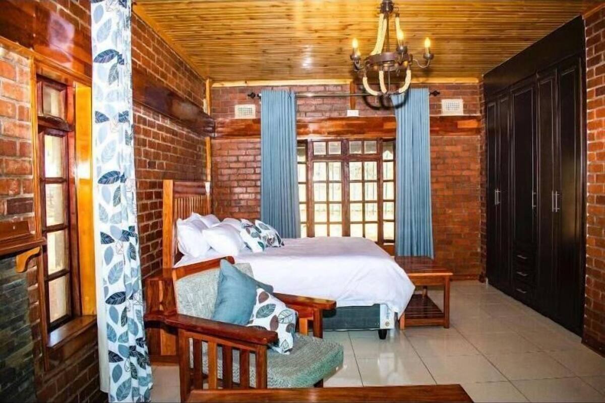 Quarto com uma cama grande, móveis de madeira, um lustre e paredes de tijolo.
