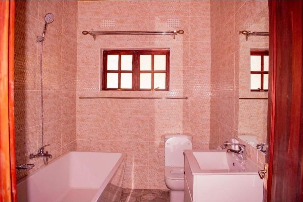 Casa de banho com banheira, sanita e janela.