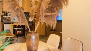Une table à manger ornée d’un vase contenant des herbes des pampas séchées, placé au centre, et entourée de chaises.