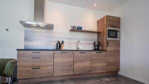 Una cocina moderna con armarios de madera, una campana de acero inoxidable, horno empotrado y cafetera.