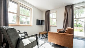 Una sala de estar moderna con un sofá, un sillón y un televisor montado en la pared.