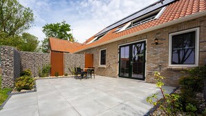 Una casa con patio, muro de piedra y fachada de ladrillo.