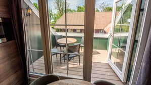 Blick aus einem Zimmer mit einer Schiebetür zu einer Terrasse, auf der ein Tisch und Stühle stehen.