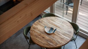 Ein runder Holztisch mit einer dekorativen Schüssel in der Mitte, umgeben von vier grünen Polsterstühlen.