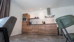 Een moderne keuken met houten kastjes, een inbouwoven en een roestvrijstalen afzuigkap.