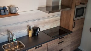 Eine moderne Küche mit Spüle aus Edelstahl, einer schwarzen Kaffeemaschine und Holzschränken.