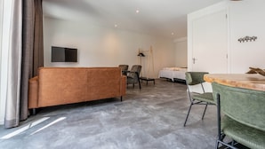A modern hotel room with a sofa, chairs, a dining table, and a bed. - De Witte Brugh- 't Fennoat (Buren)