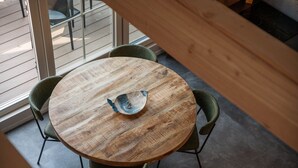 A round wooden table with a unique metal bowl centerpiece, surrounded by four green chairs. - De Witte Brugh - Nijlânsrèèd (Buren)