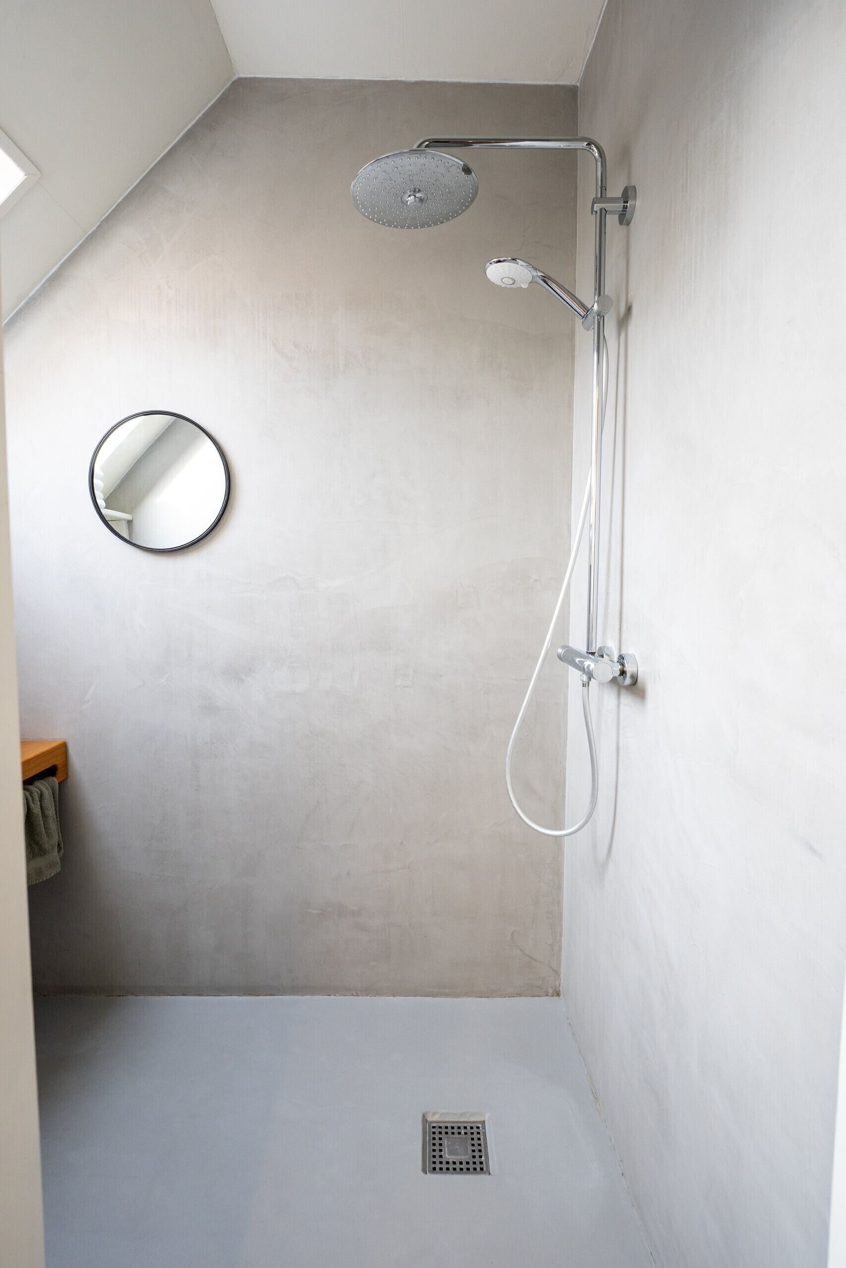 A shower with a handheld showerhead and a wall-mounted faucet.