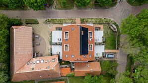 Luchtbeeld van een woongebied met meerdere gebouwen, waaronder een groot huis met pannendak en enkele kleinere constructies.