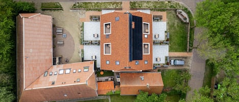 An aerial view of a residential area with multiple buildings, including a large house with a tiled roof and several smaller structures.