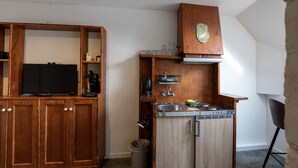 A compact kitchen with a built-in stove, sink, and a small refrigerator. - De Witte Brugh - Studio 4 (Buren)