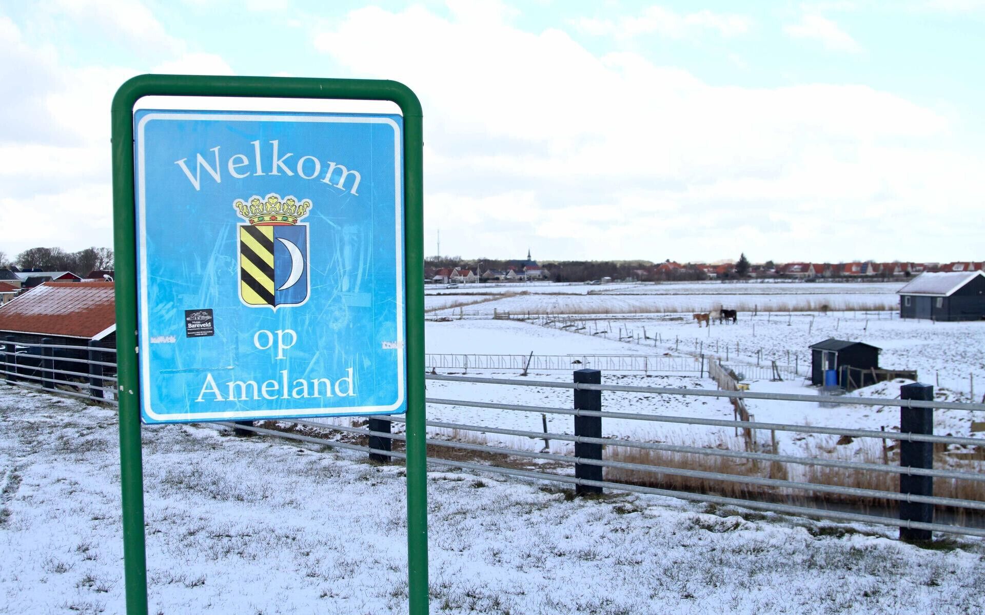 A sign welcoming visitors to Op Ameland, featuring a coat of arms.