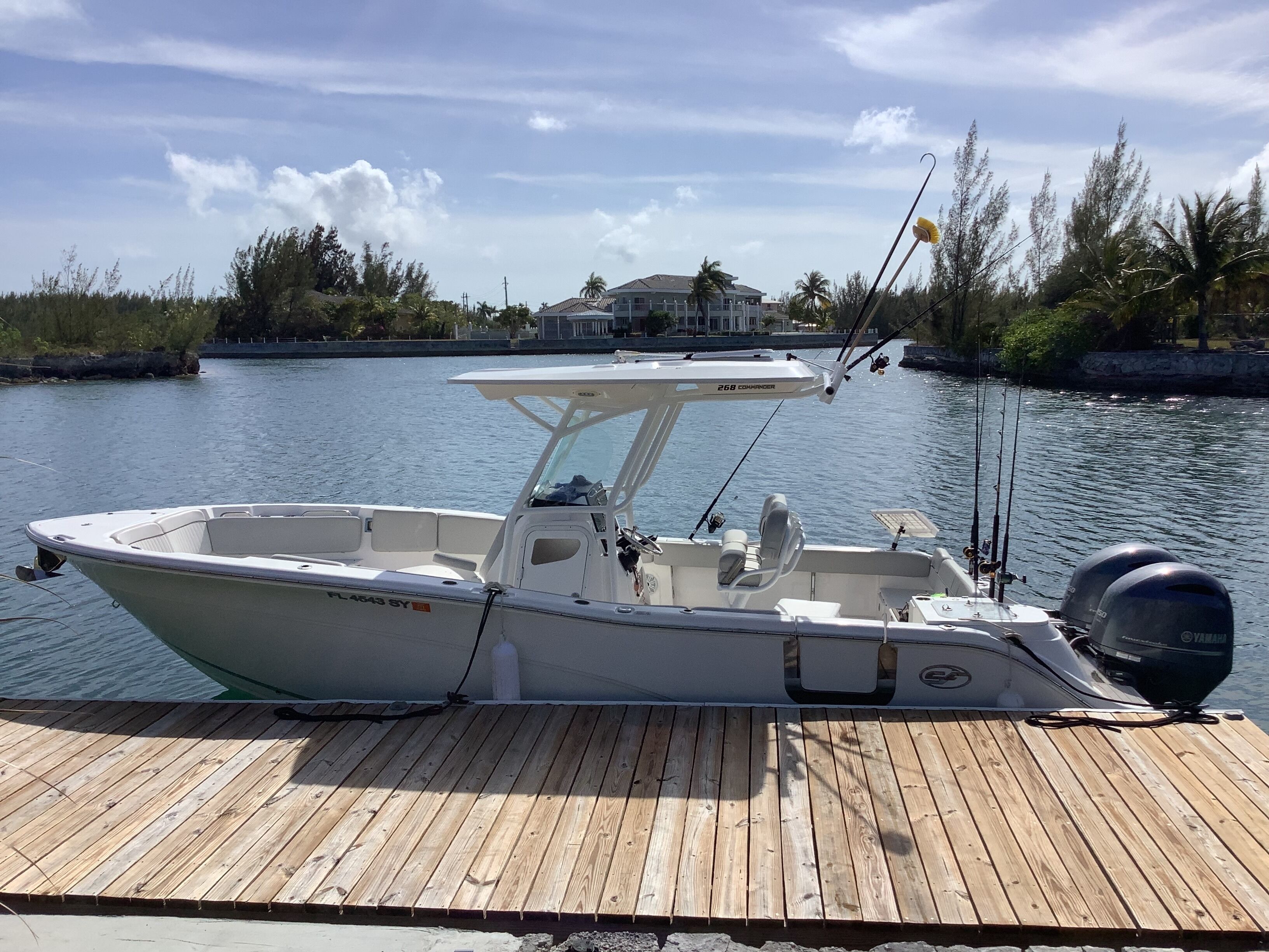 A boat docked on a wooden pier with a house in the background.