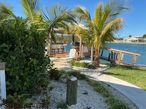 A deck with a grill, a pool, and a view of the water. - Charming New Blue Studio on water with dock, WiFi & AC in fun time Freeport (Freeport)