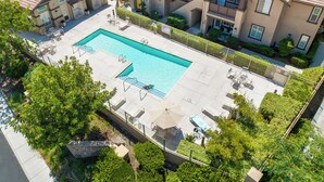 Un complejo residencial con piscina, mobiliario exterior y un jardín bien cuidado.