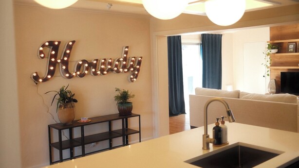 Une cuisine moderne dotée d’un grand îlot central, d’un évier et d’un panneau décoratif fixé au mur.