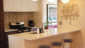 Une cuisine moderne dotée d’un îlot central, de tabourets de bar et d’un crédence décorée.