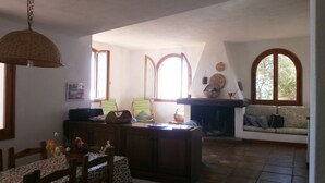 Ein gemütliches Wohnzimmer mit Kamin, einer Essecke mit Tisch und Stühlen sowie einer Couch.