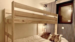 A bunk bed with a wooden frame, two pillows with wolf designs, and a window with vertical blinds.