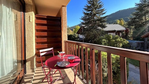 Ein Balkon mit Tisch und Stühlen, Blick auf einen Berg, und ein Gebäude im Hintergrund.